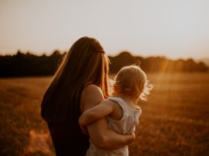 Mother holding daughter, standing in meadow