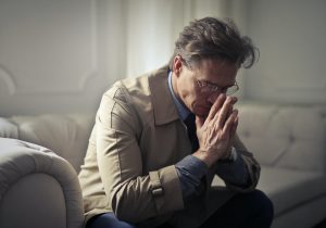 Sad businessman thinking about problem, on couch in living room