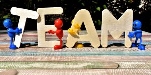 Little characters holding up letters that spell the word team