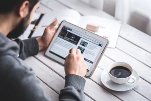 Man on ipad with coffee next to him