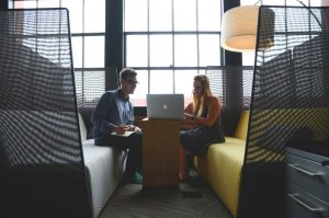 Man and woman studying together, huddled around laptop