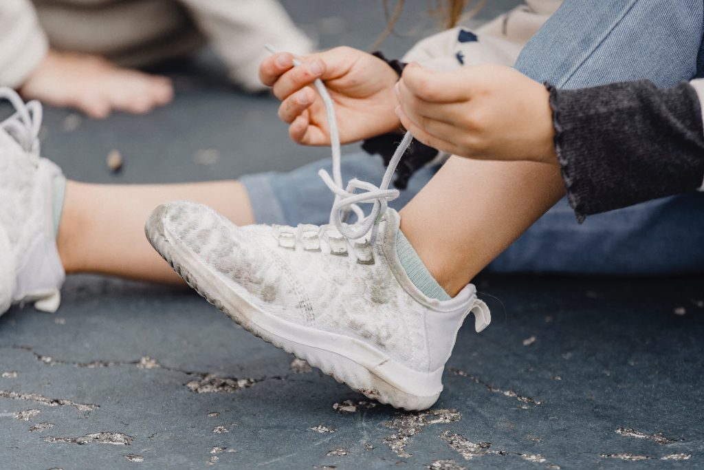 A child trying to lace their shoe.