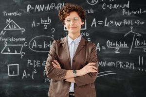 A woman in suit standing in front of a blackboard with mathematical equations