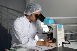 A man in lab coat looking into microscope.