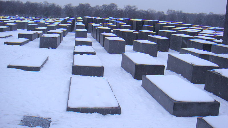 Photo of many slabs and blocks in the ground covered in snow. This is the Memorial to the Murdered Jews of Europe in Berlin