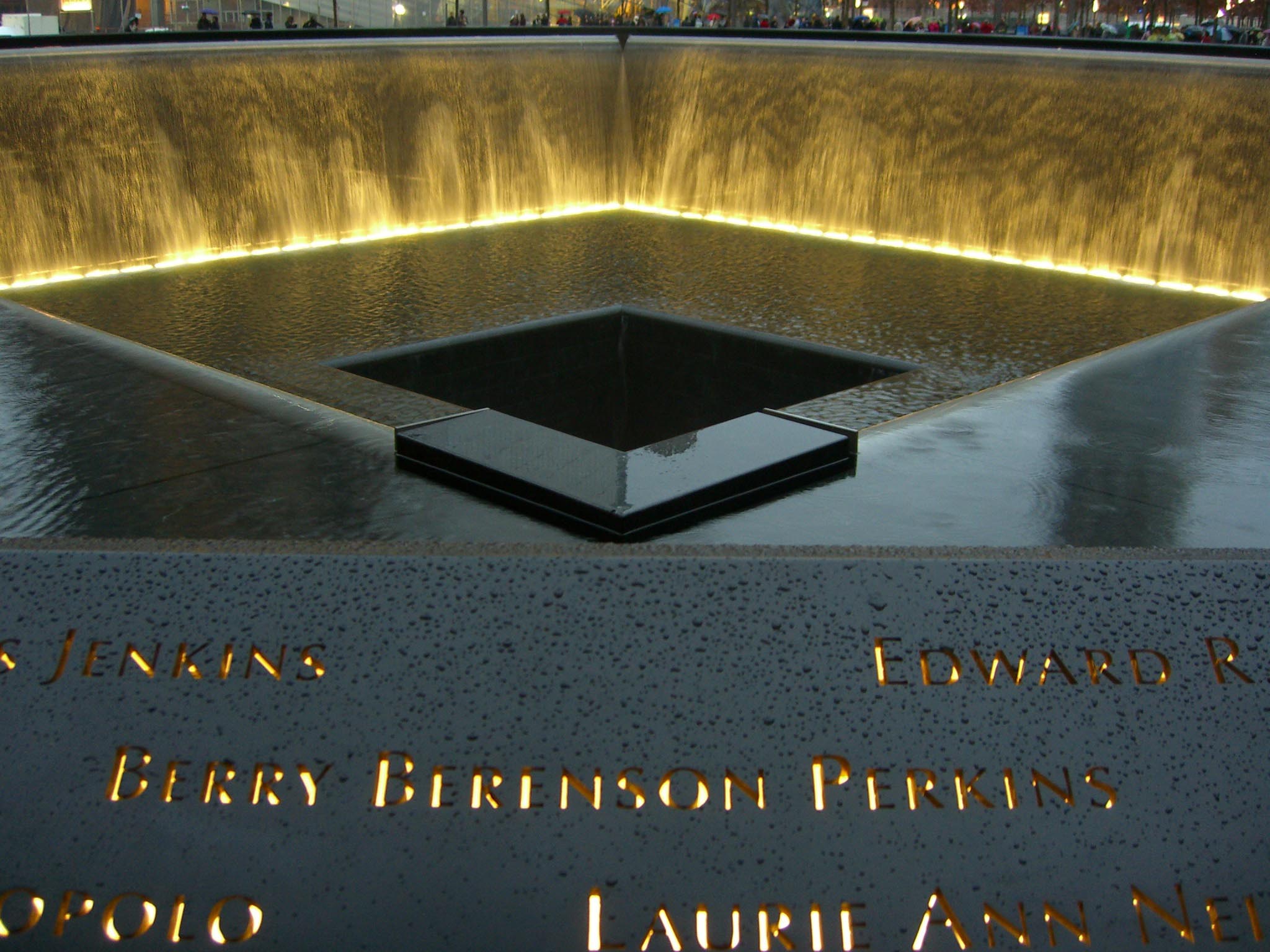 Photo of the The 9/11 Memorial - a hole where the tower was, surrounded by light and white, with the camera zooming on a victim's name.