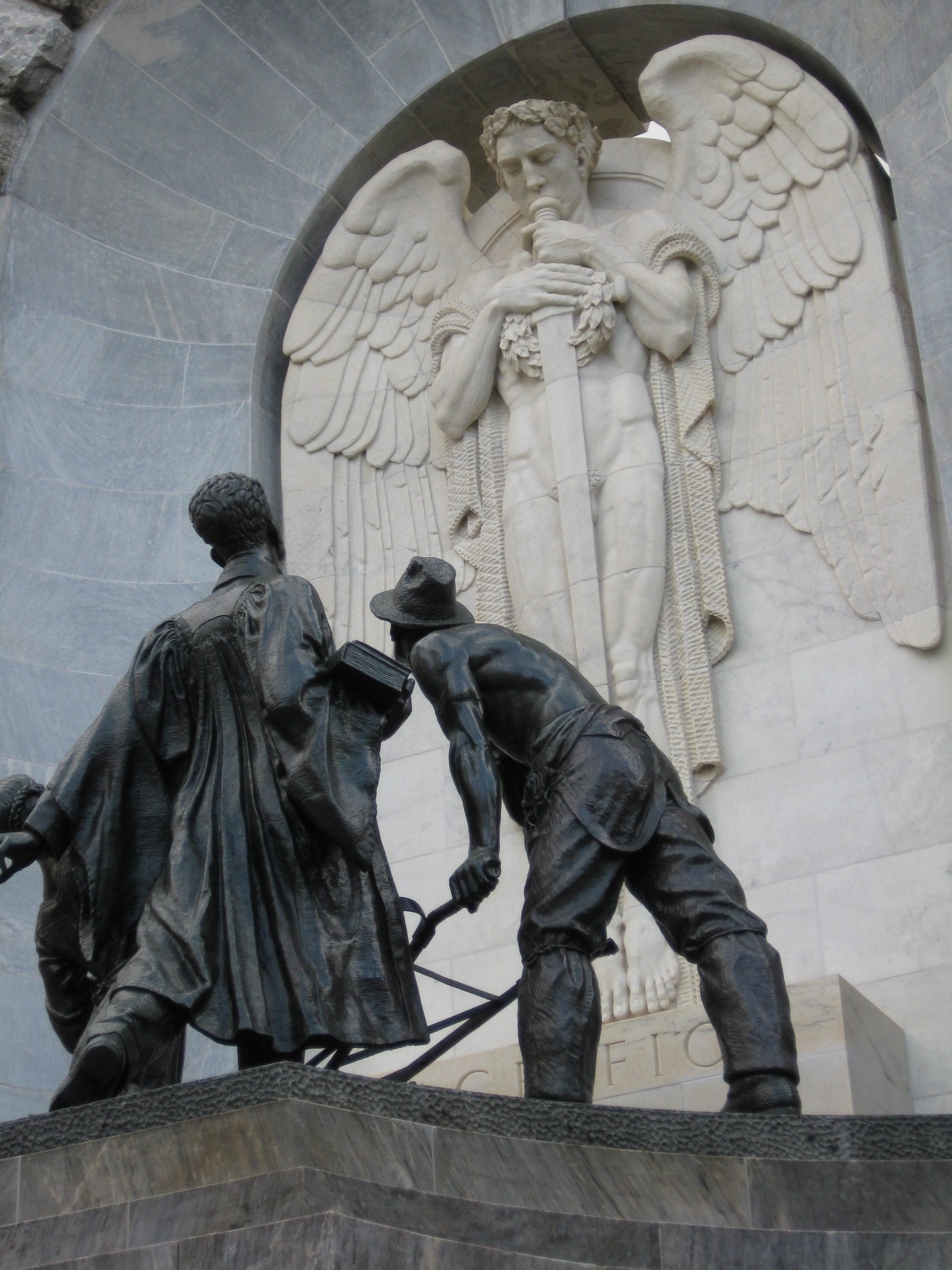 The Spirit of Duty appearing before a sculptural group representing the youth of South Australia in the form of the girl, the student and the farmer. The work, by Rayner Hoff (1894–1937), forms one side of the South Australian National War Memorial, unveiled in 1931.