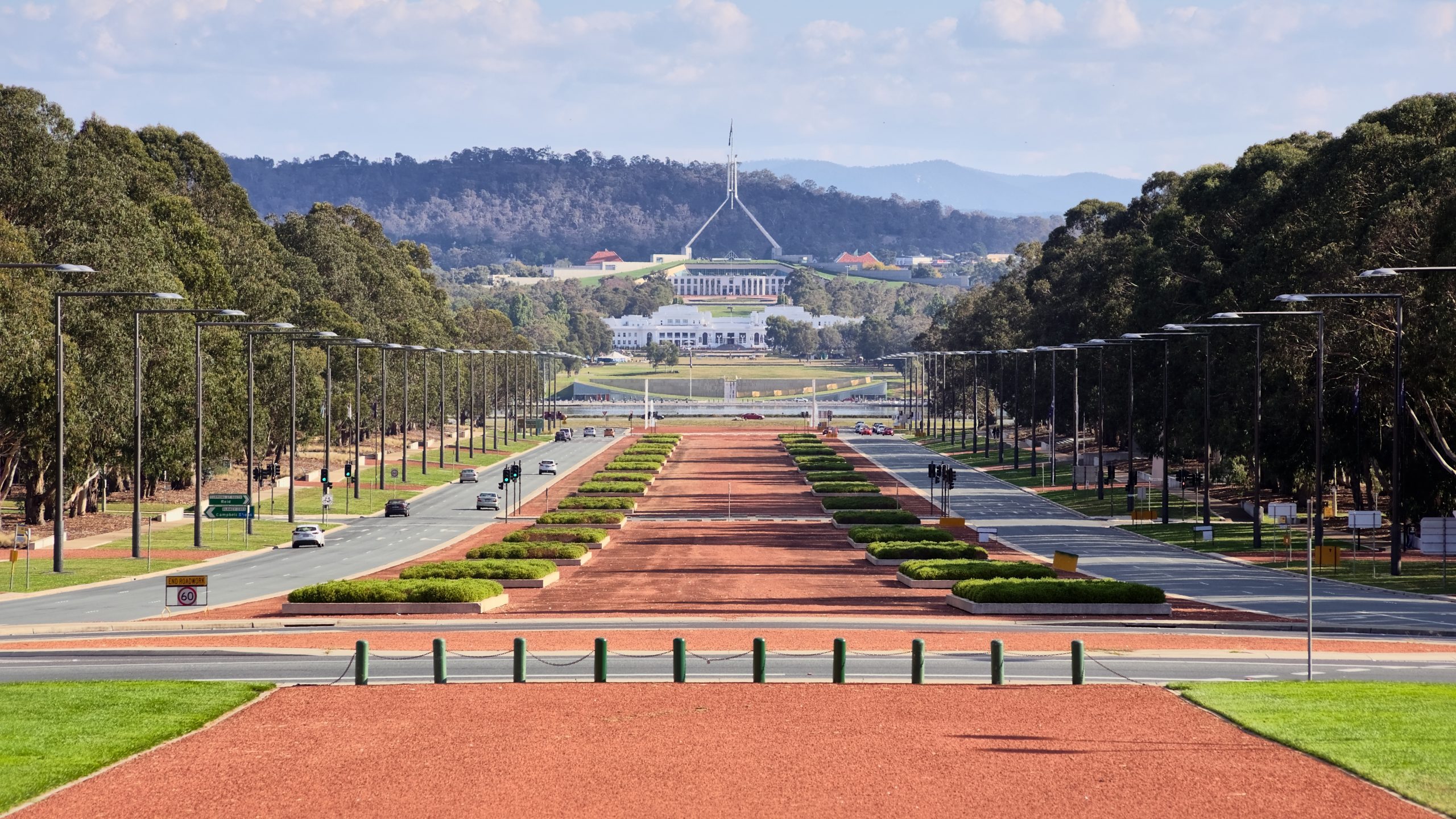 Photo of Anzac Parade from the Australian War Memorial in Canberra, ACT. In the distance is Old Parliament House, and behind that is the new Parliament House.