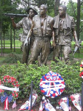 Three bronze statues in a garden. One had a rifle over its shoulder