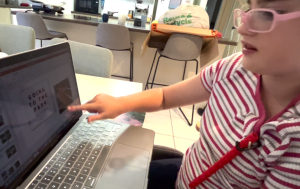 child pointing at laptop screen