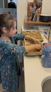 Child touching Anzac biscuits on tray