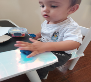 child sitting at a table playing with playdough