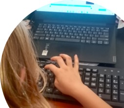 child typing on a keyboard in front of a laptop