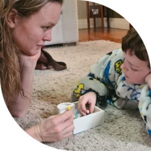 woman looking at boy while both are playing with lego on the carpet