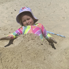 Child at beach buried in sand