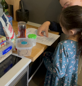 woman helping child read recipe with ingredients nearby