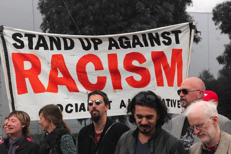 People next to a sign that says stand up against racism