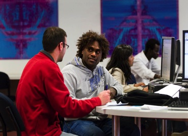 Image of two men - one white and one dark at a computer