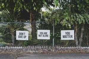 Signs on a fence that say 'Don't give up,' 'You are not alone' and 'you matter'
