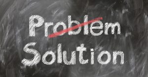 The words problem and solution are on a chalkboard and the word problem is crossed out.