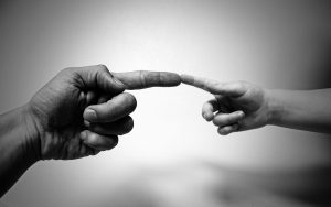 A decorative image of an adult and child touching index fingers.