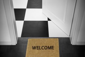 A decorative image of an open door with a welcome mat.